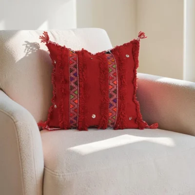 Red Moroccan sabra cactus silk pillow cover with handwoven Berber patterns on a neutral armchair