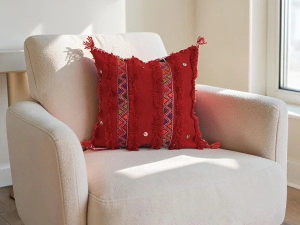 Red Moroccan sabra cactus silk pillow cover with handwoven Berber patterns on a neutral armchair