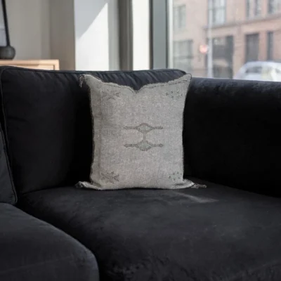 Two grey handwoven sabra silk cushions styled on a black sofa