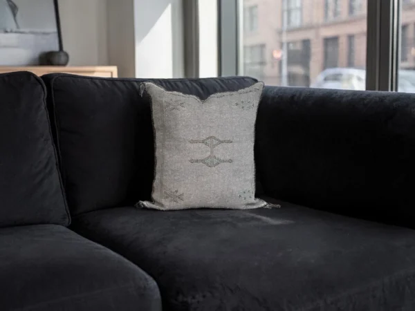 Two grey handwoven sabra silk cushions styled on a black sofa