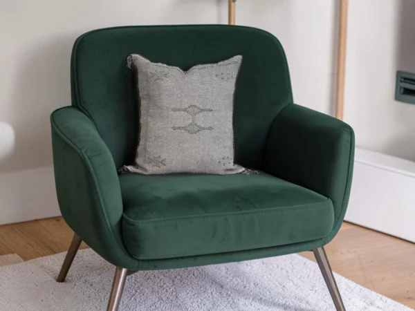Grey Moroccan sabra silk cushion styled on an emerald green velvet armchair