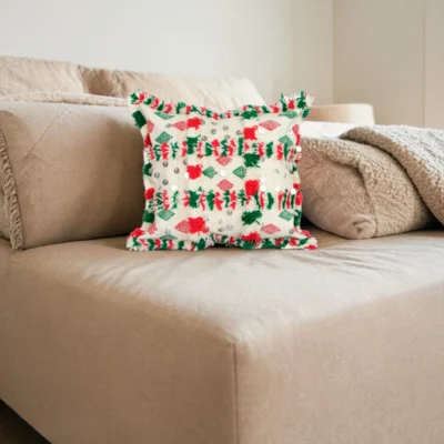 Handwoven Berber cushion placed on a beige sofa with red and green diamond motifs