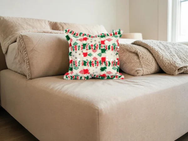Handwoven Berber cushion placed on a beige sofa with red and green diamond motifs
