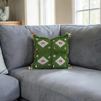 Green Moroccan Berber wool pillow on grey sofa in modern Scandinavian living room interior with soft natural lighting
