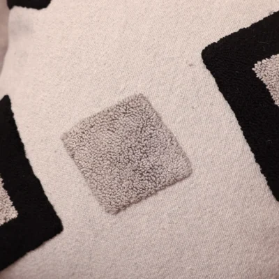 Close-up detail of Moroccan hand-tufted pillow cover showing raised black diamond Berber geometric motifs on ivory base