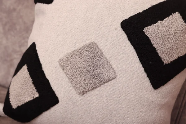 Close-up detail of Moroccan hand-tufted pillow cover showing raised black diamond Berber geometric motifs on ivory base