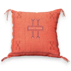 Front view of the rust orange Moroccan sabra silk pillow with a central indigo Amazigh Tifinagh motif and corner tassels