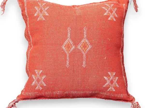 Burnt orange sabra cactus silk throw pillow cover with ivory Berber XX star motifs, a central twin-flame diamond motif, and fringed corners, handwoven in Marrakech.