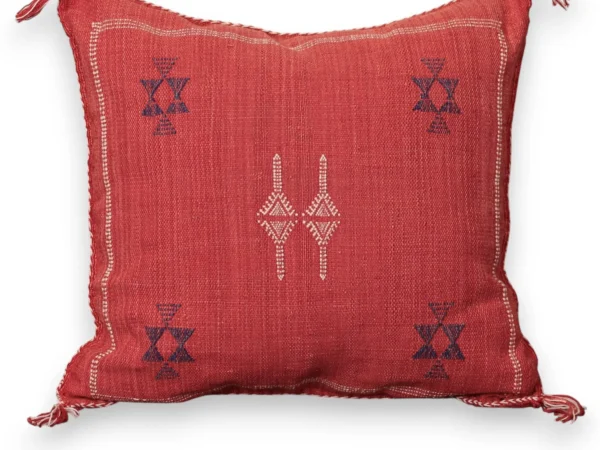 Handwoven coral red sabra cactus silk throw pillow with a navy blue Berber twin dagger motif at the center and navy chalice star motifs in the corners