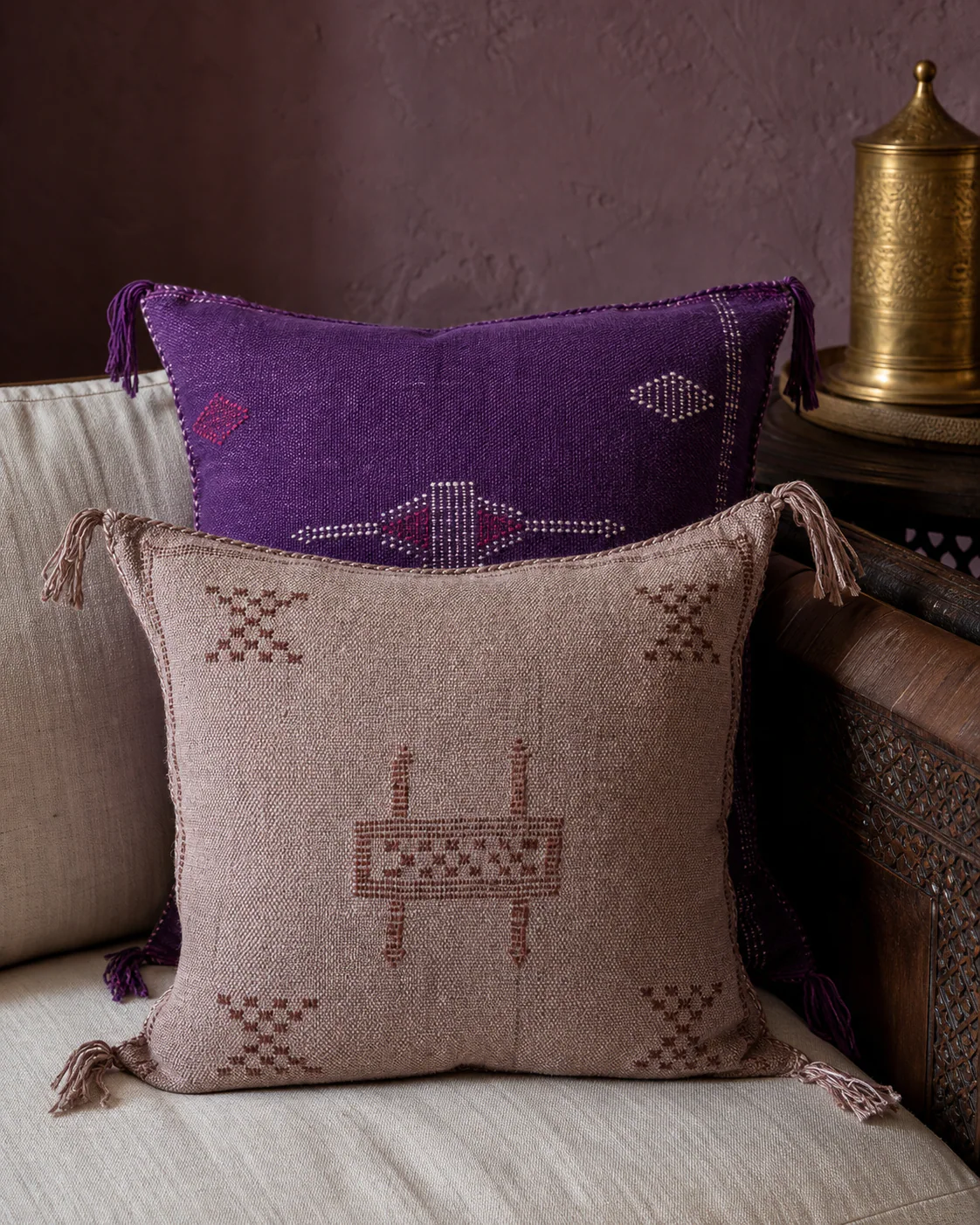 Layered amethyst and dusty-mauve Moroccan Sabra pillows on an ivory linen sofa