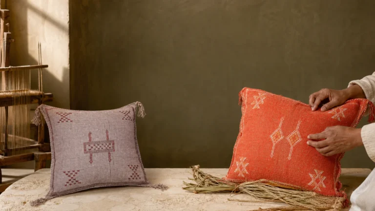 Authentic Moroccan Sabra silk pillows inspected by an artisan in a sunlit weaving atelier